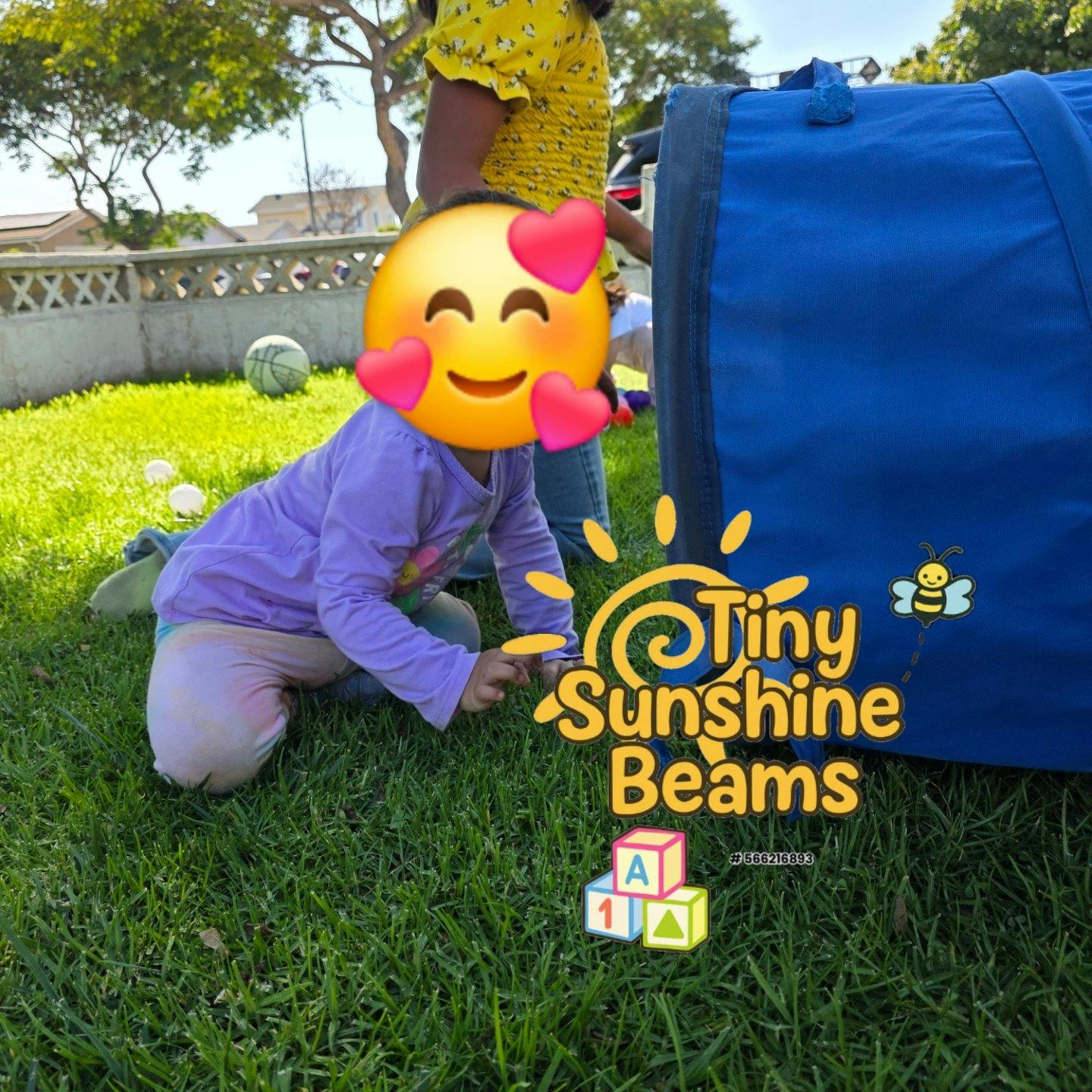 Child kneeling on grass next to a blue play tunnel