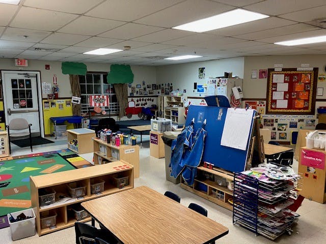 Classroom with tables, chairs, art supplies, and colorful decorations