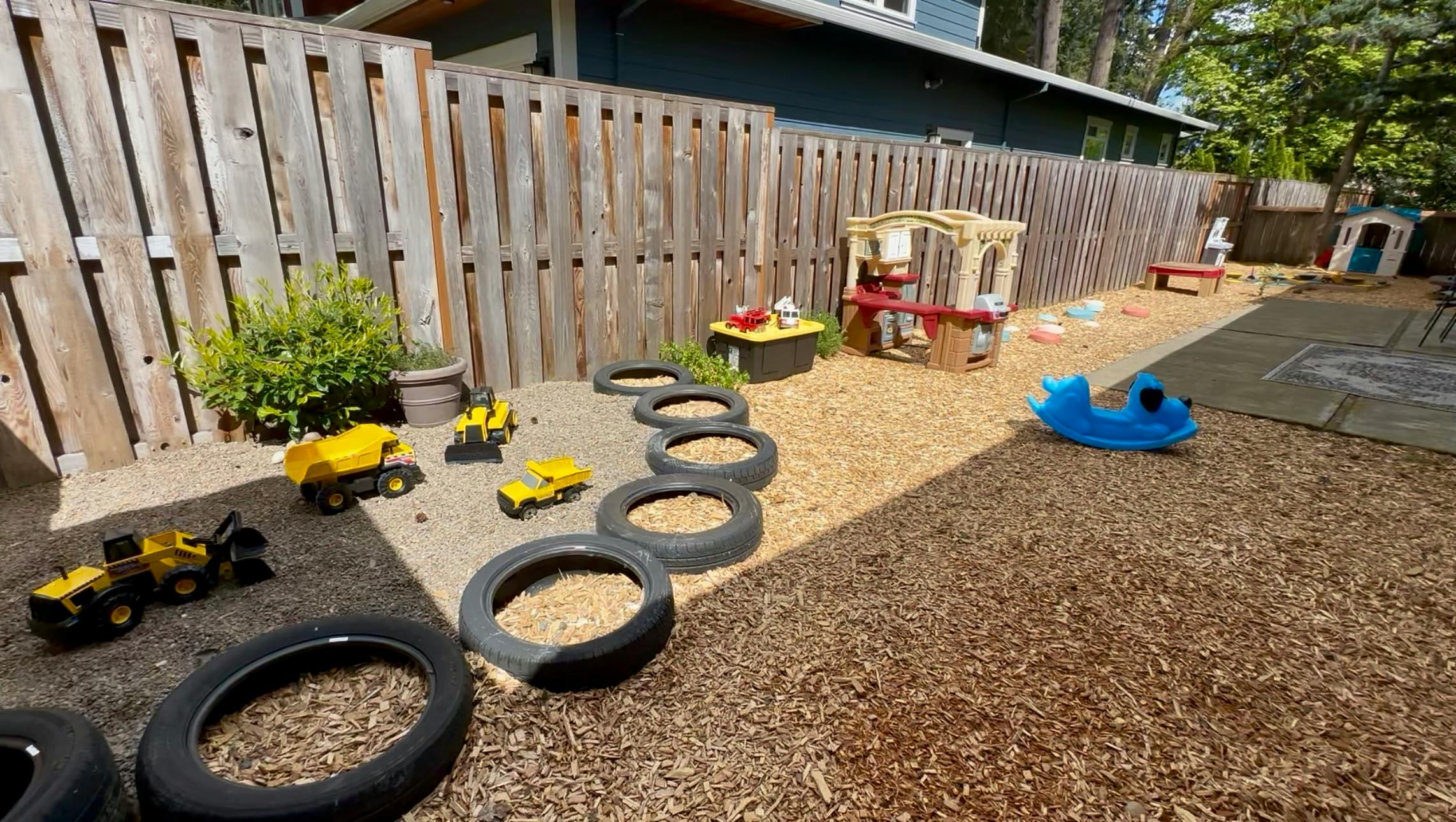 Outdoor play area with tires, toy trucks, and playhouses