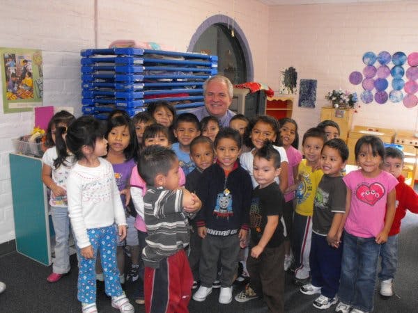 Adult person standing with a group of children in a classroom