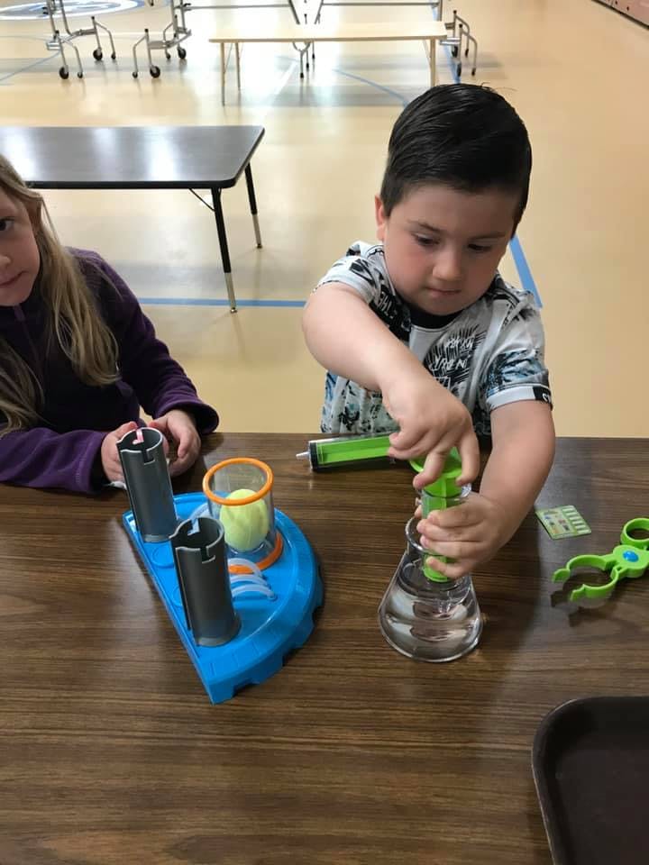 Child using a green pump to move liquid in a science experiment