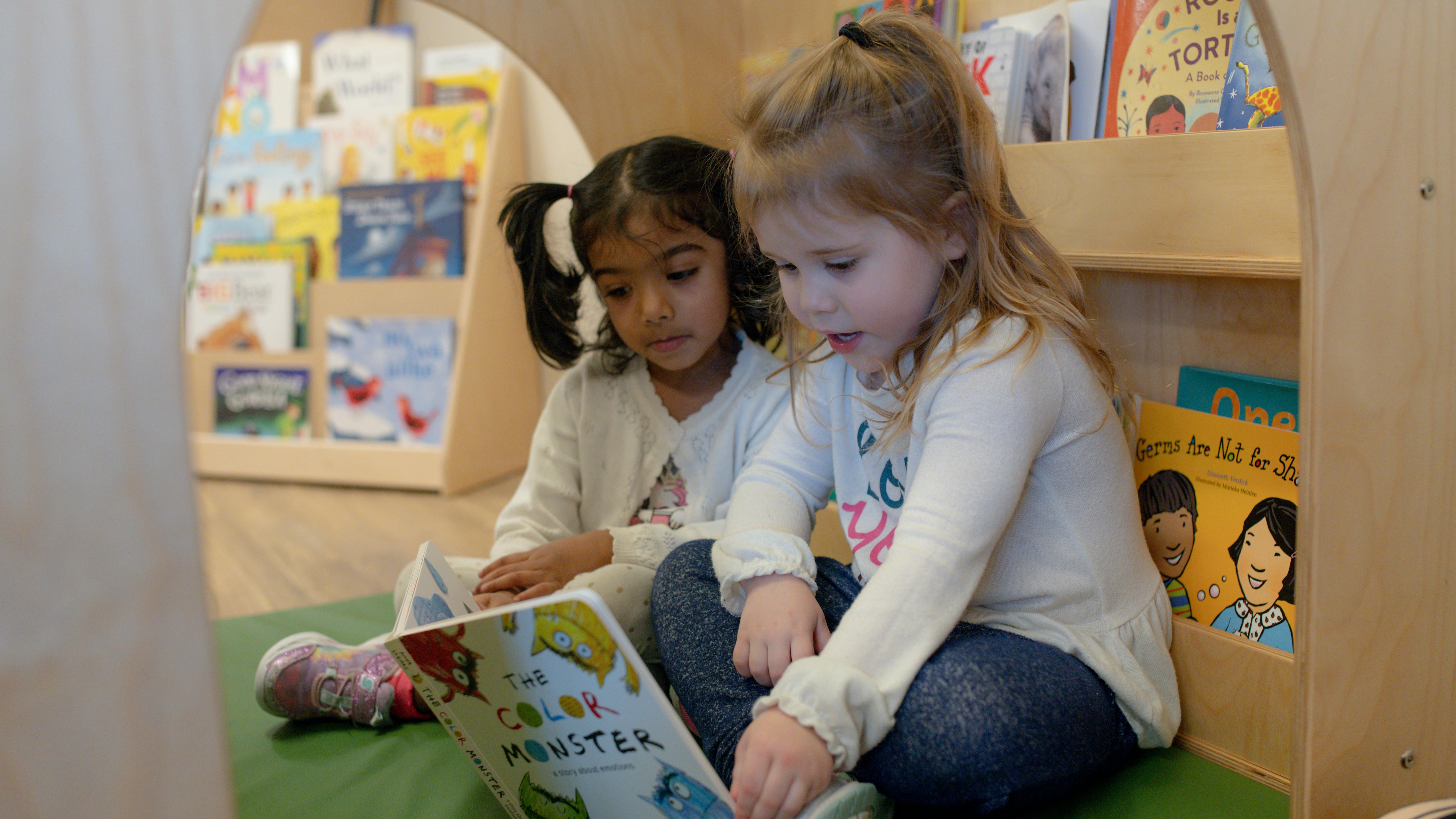 Two children reading a book together in a classroom