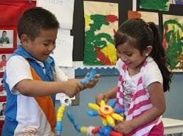 Two children playing with toys in a classroom