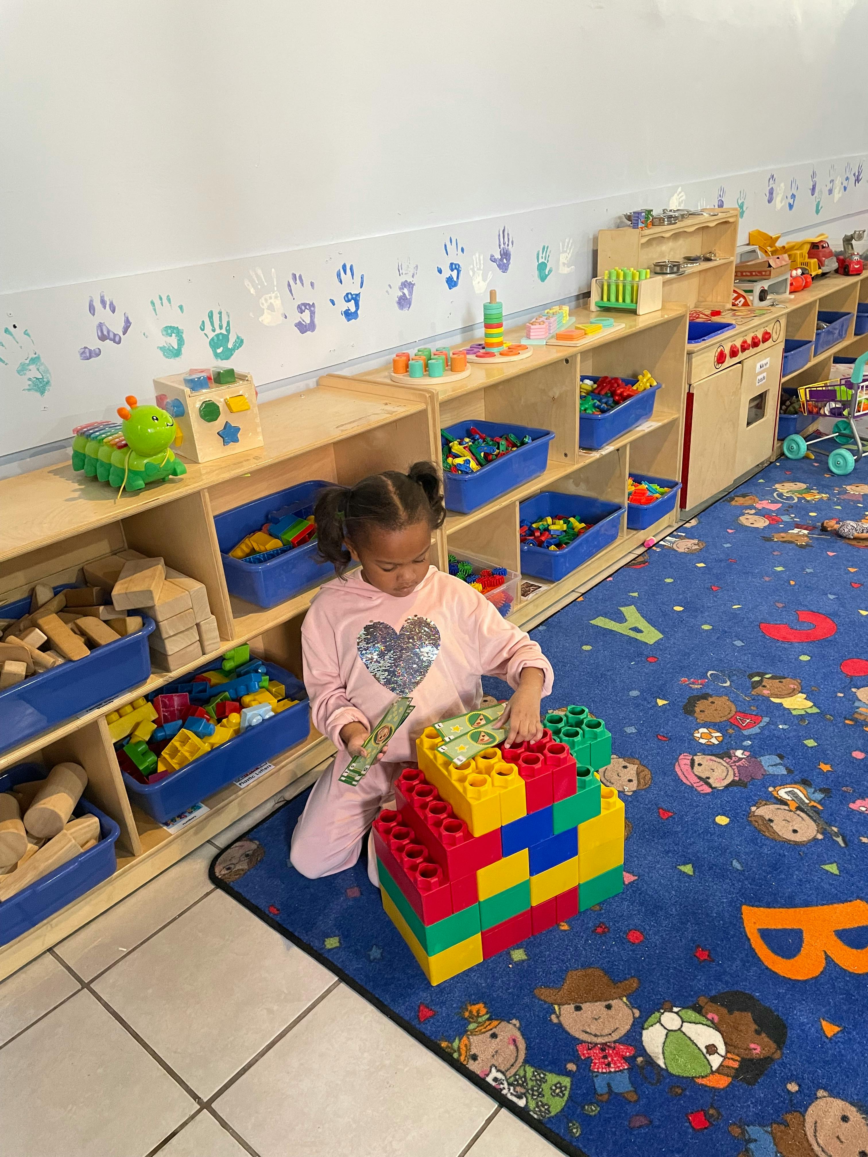 Child playing with large colorful building blocks in a classroom
