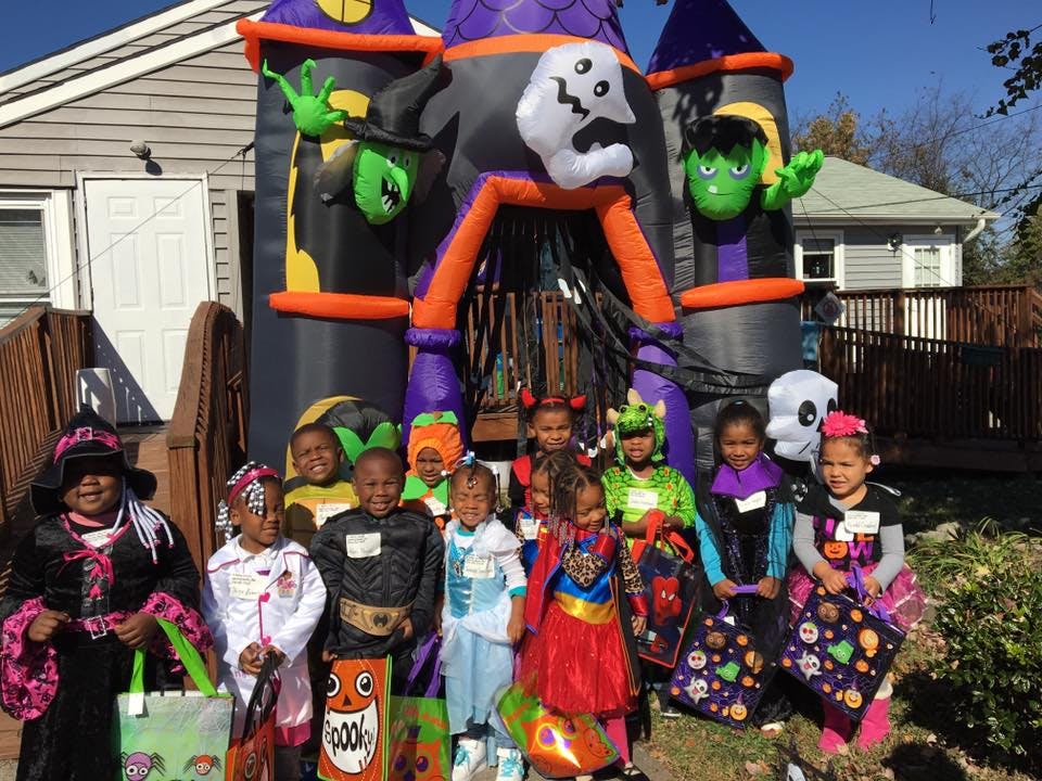 Children in Halloween costumes standing in front of an inflatable haunted house