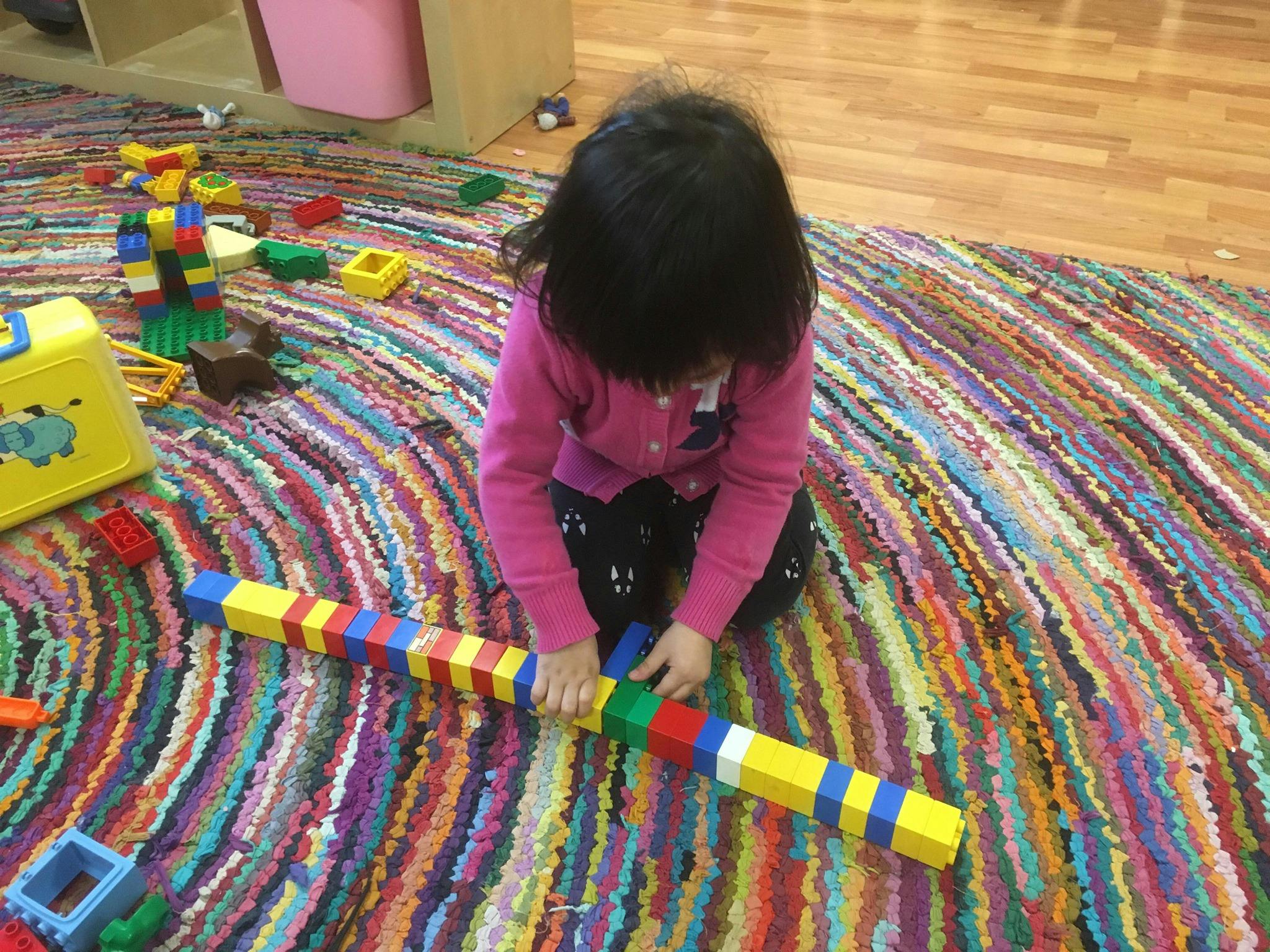 Child playing with colorful building blocks on a patterned rug