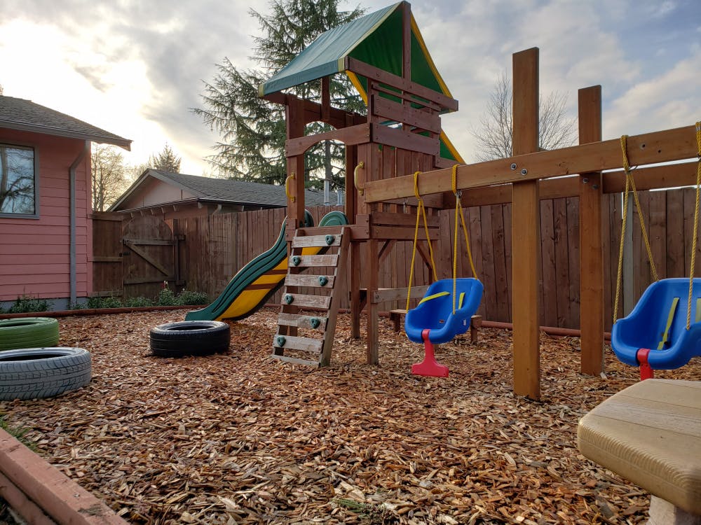 Wooden playground structure with slide and swings in a yard
