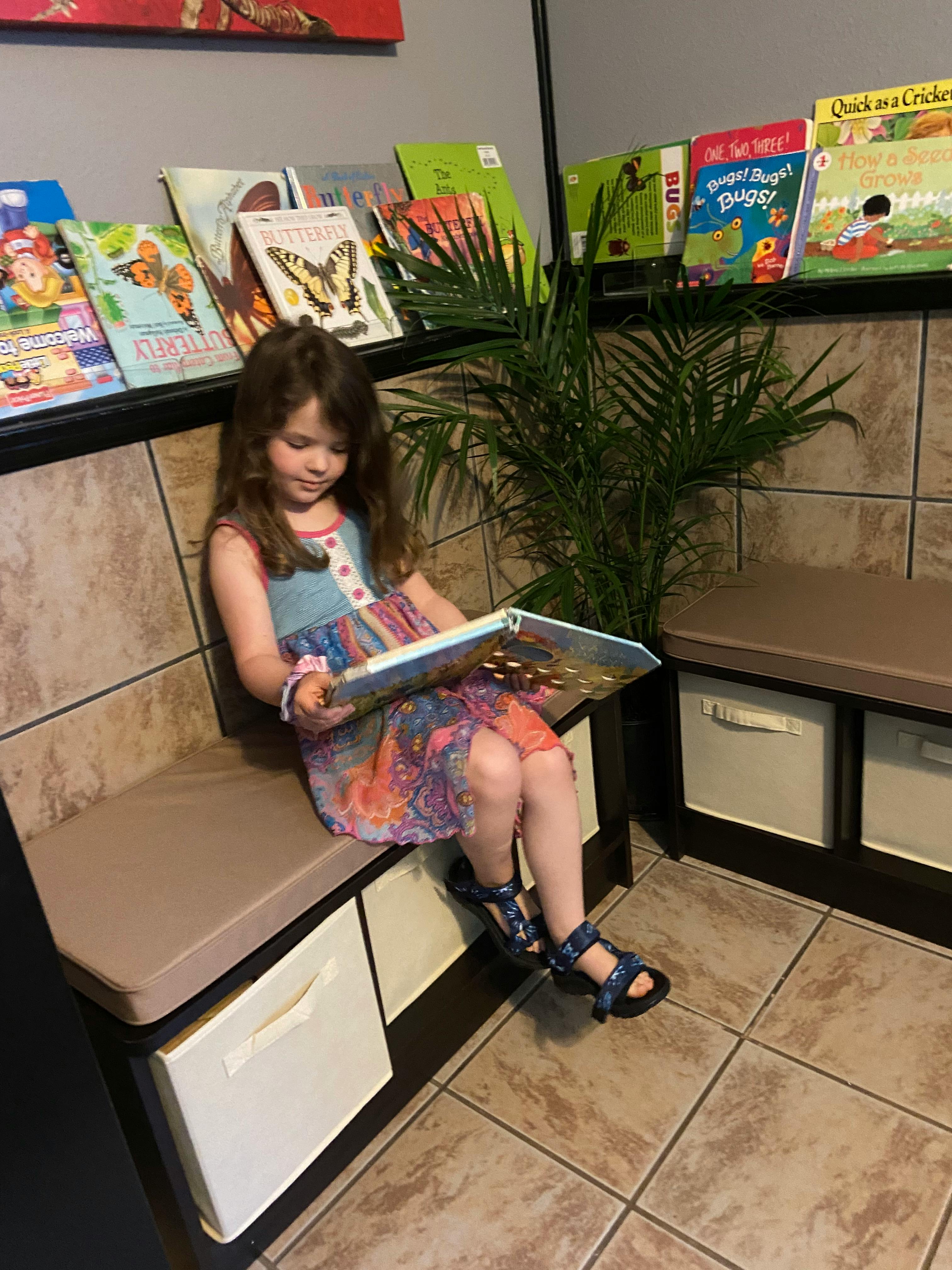 Child sitting on a bench and reading a book
