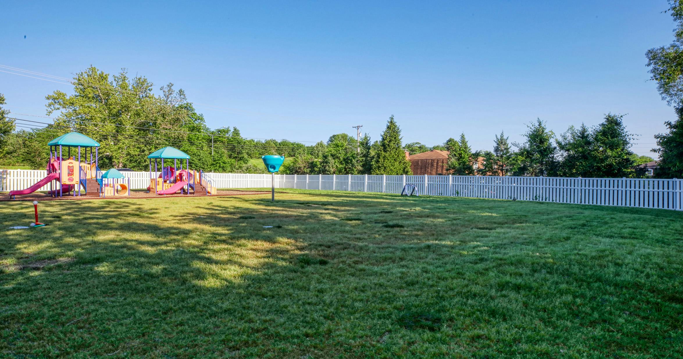 Empty playground with colorful play structures and a green lawn