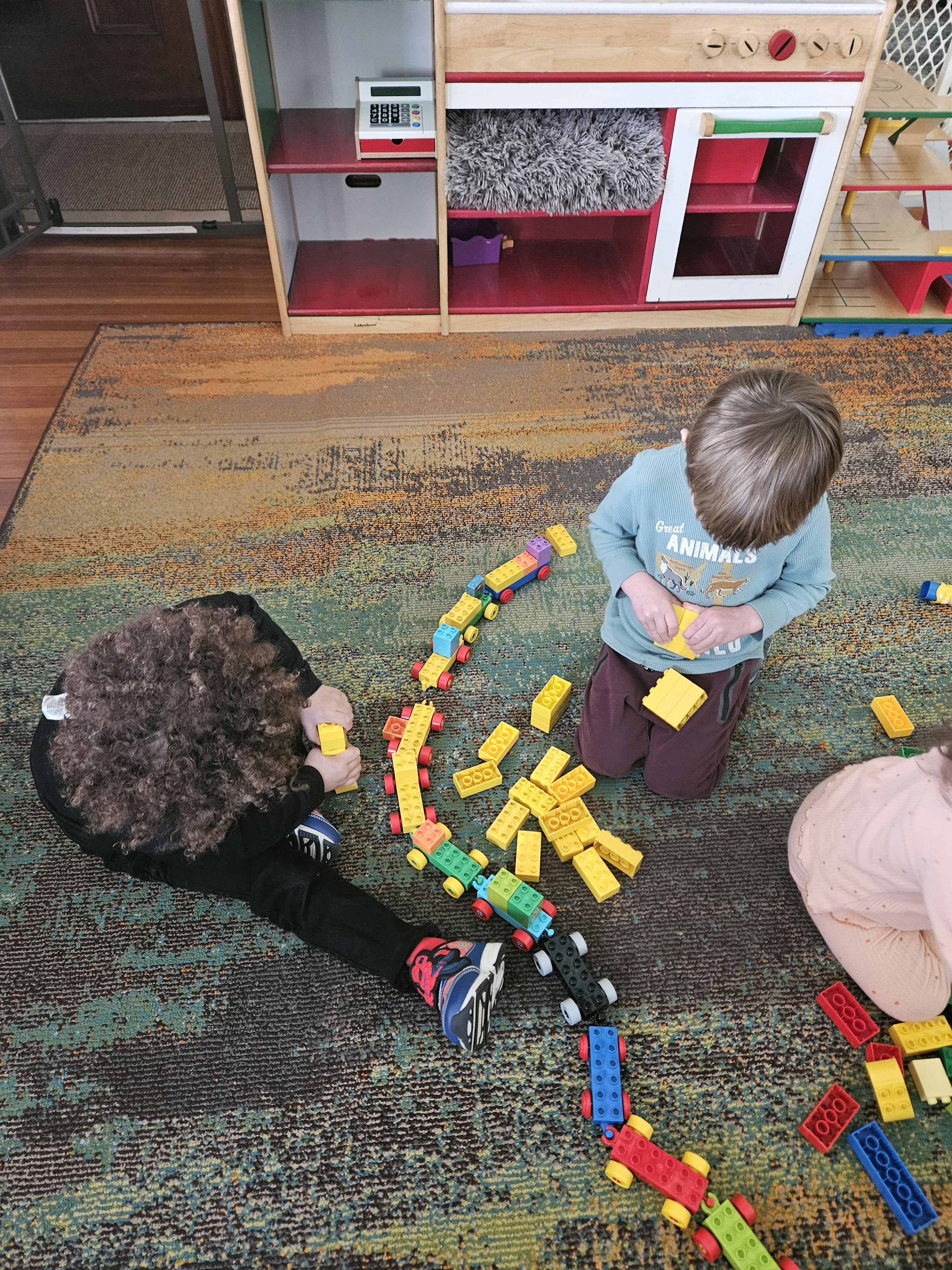 Children playing with colorful building blocks on a rug