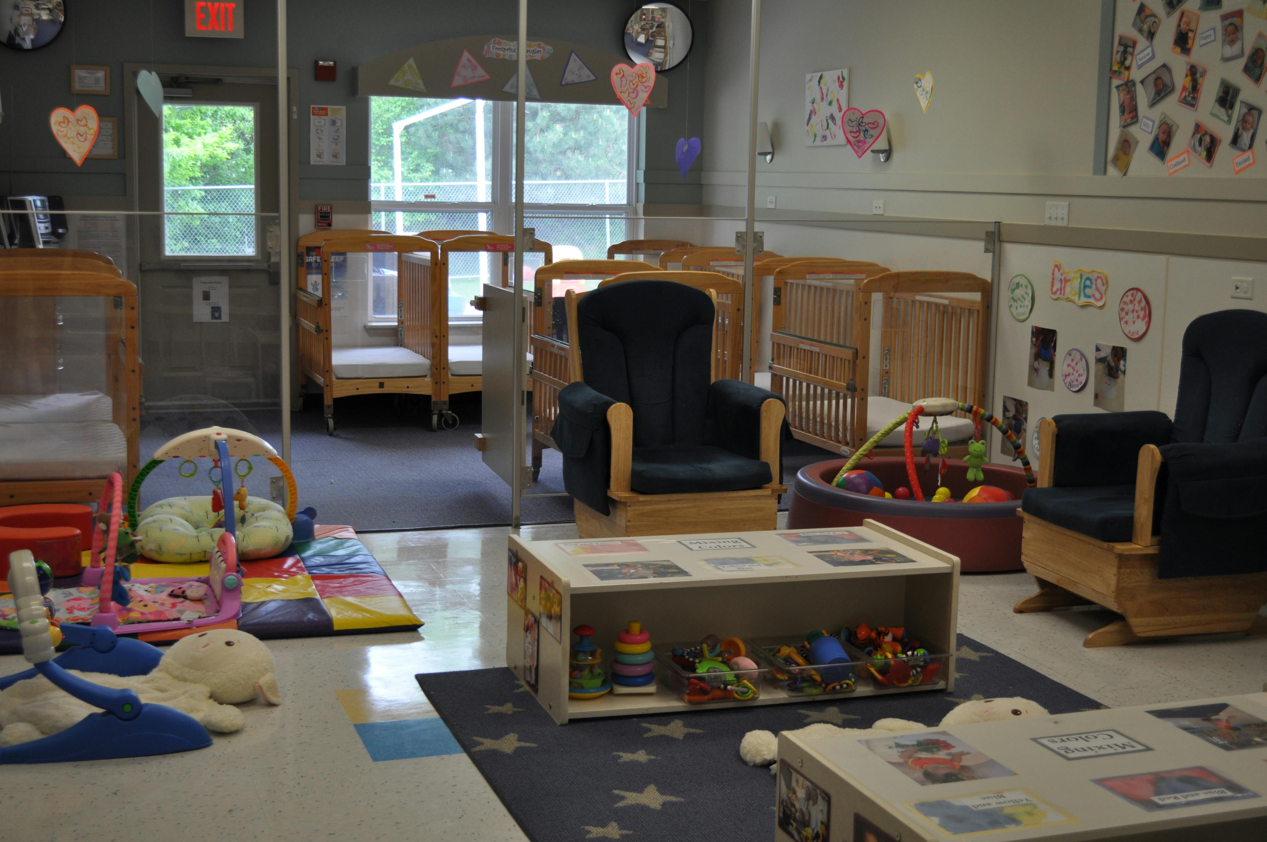 A childcare nursery room with multiple cribs, a rocking chair, and toys
