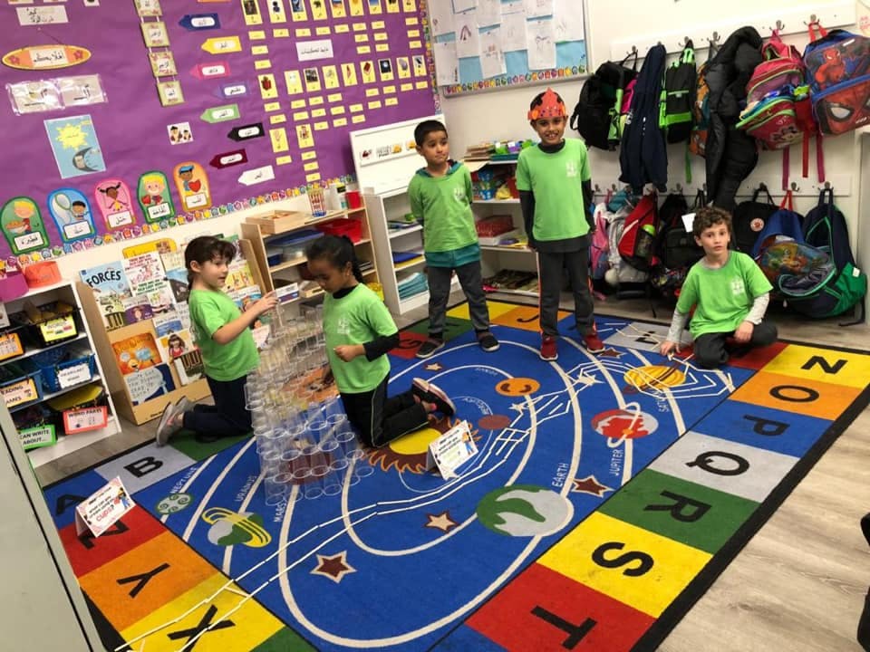 Children playing on a colorful rug in a classroom