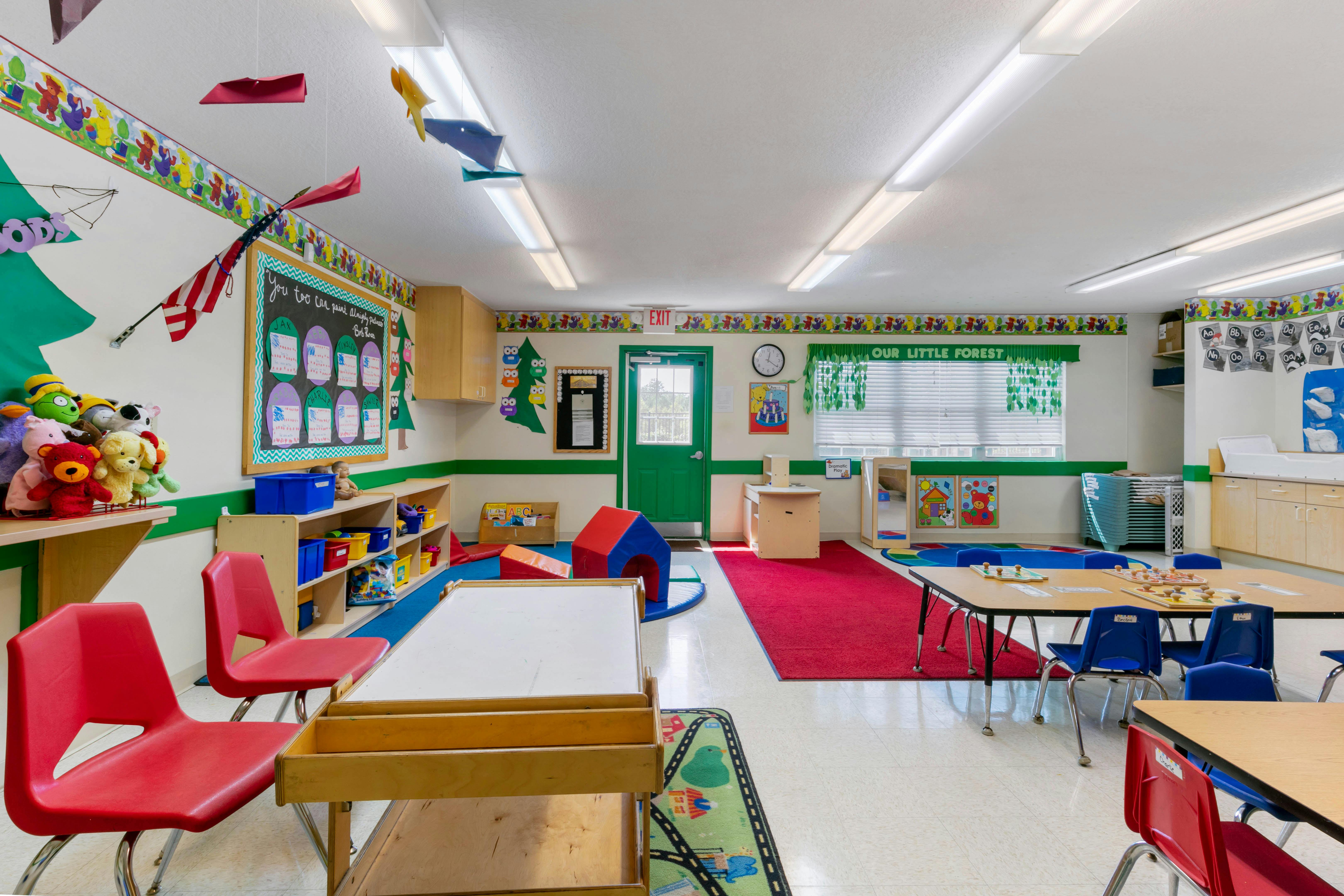 Colorful preschool classroom with tables, chairs, and play areas
