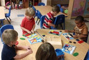 Children playing with puzzles at tables in a classroom