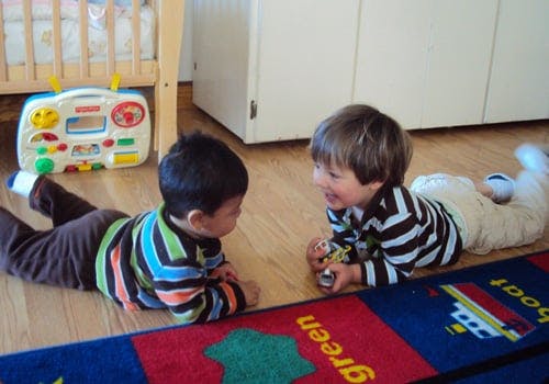 Two children lying on the floor facing each other