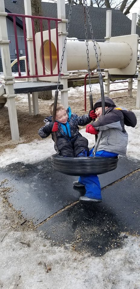 Two children on a tire swing at a playground