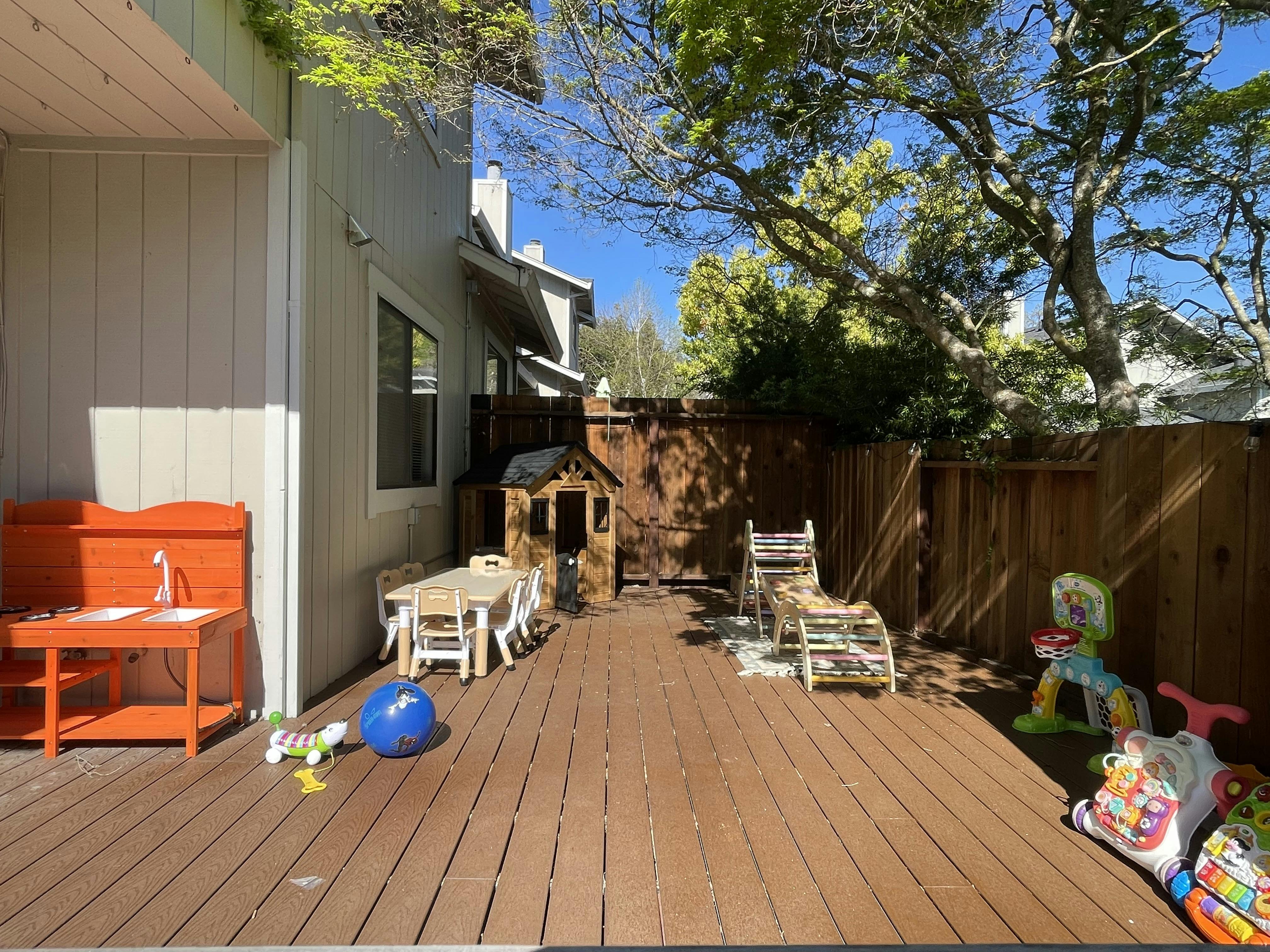 Deck with children's playhouse, table and chairs, and outdoor toys