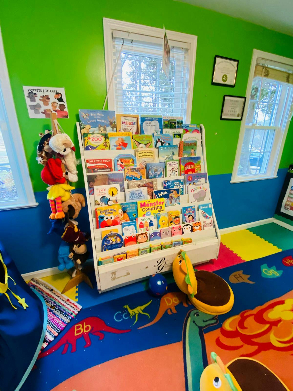 Children's classroom with a bookshelf, puppets, and a colorful rug
