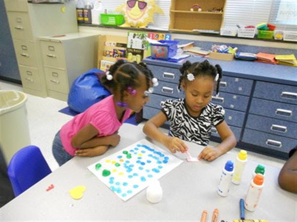Two children at a table with craft supplies