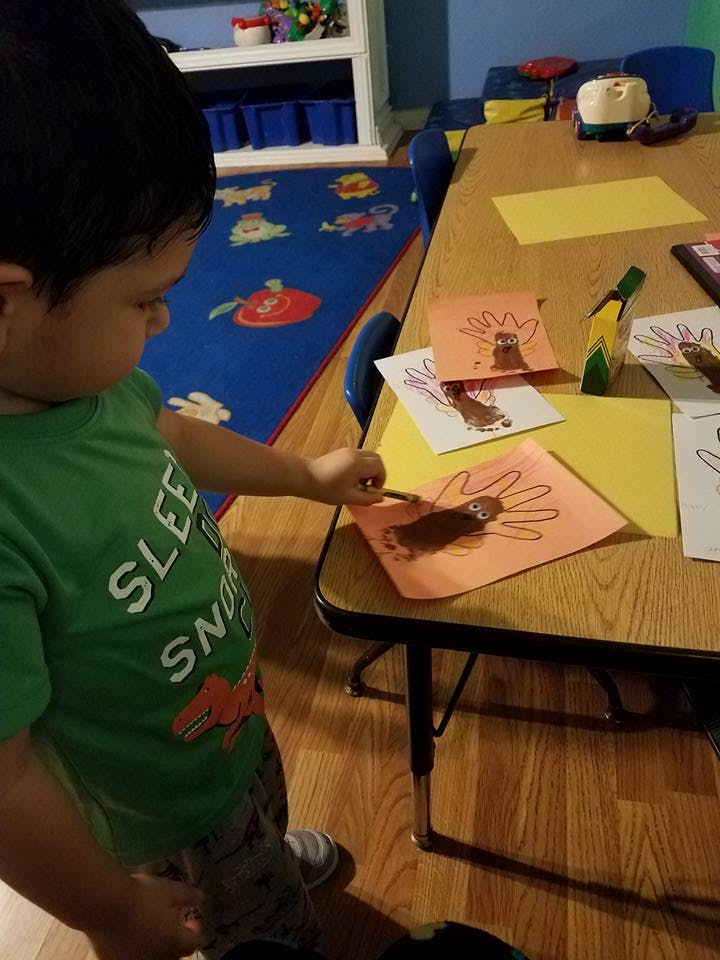 Child drawing on a paper turkey craft in a classroom