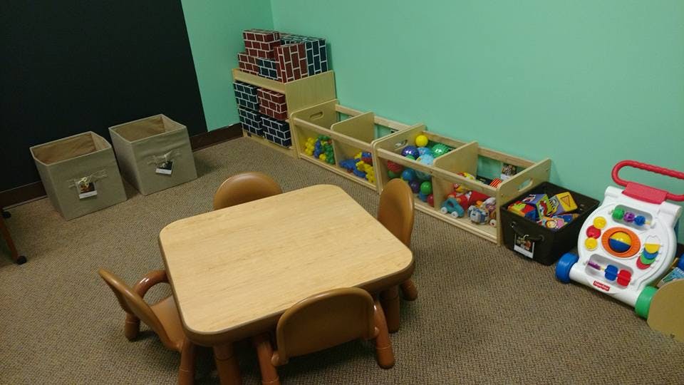 Child-sized table and chairs in a room with toy storage