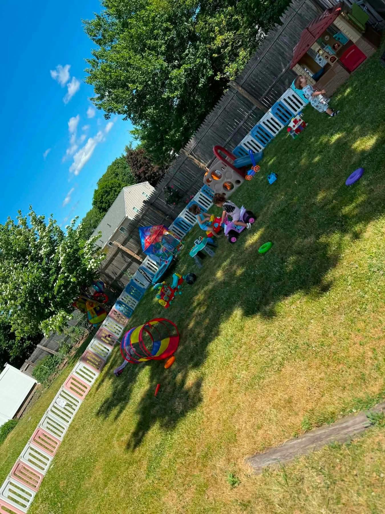 Children playing with toys in a fenced backyard