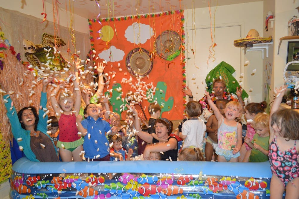 People and children in an inflatable pool with confetti falling