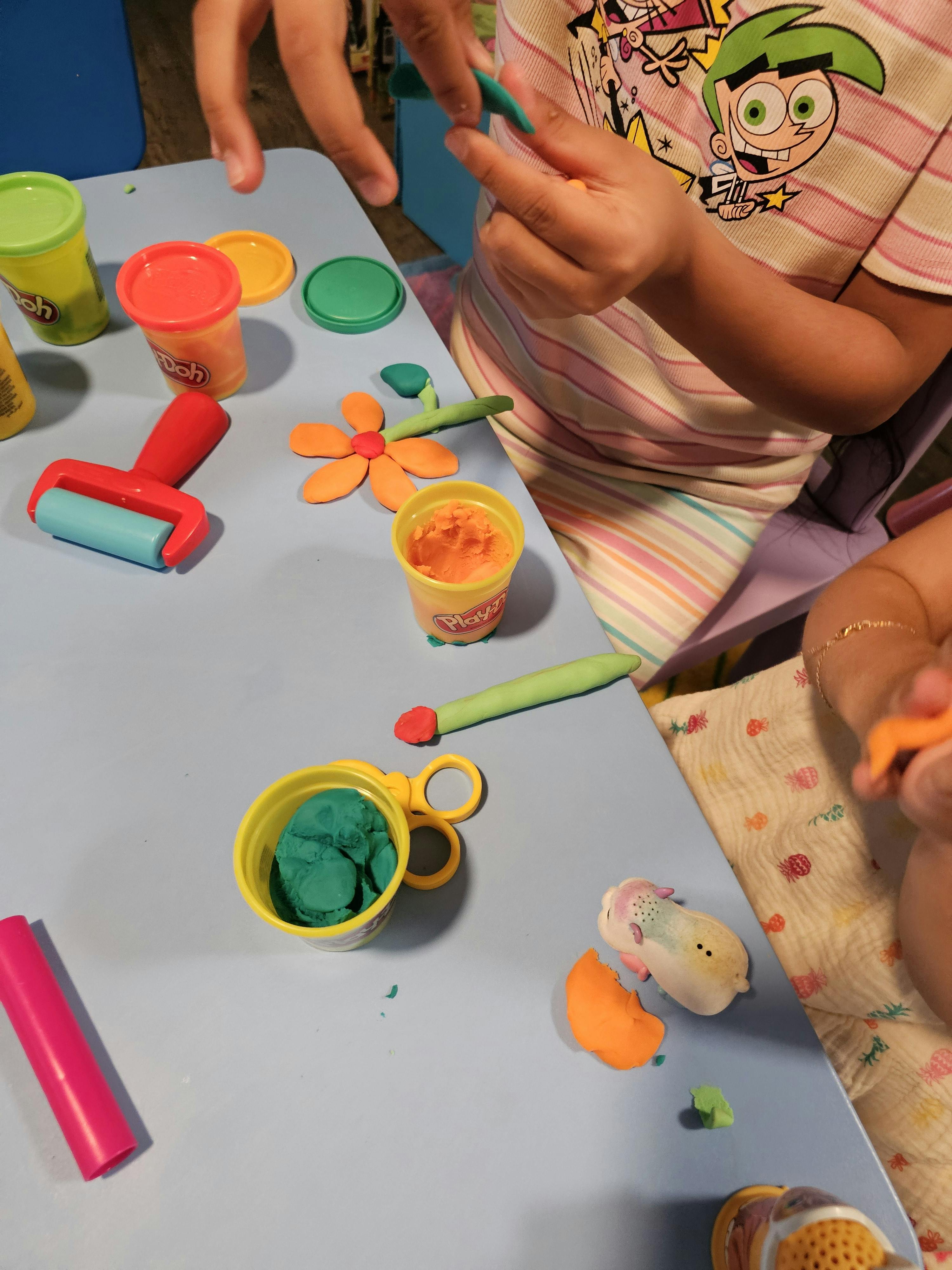 Child playing with modeling clay and tools on a table