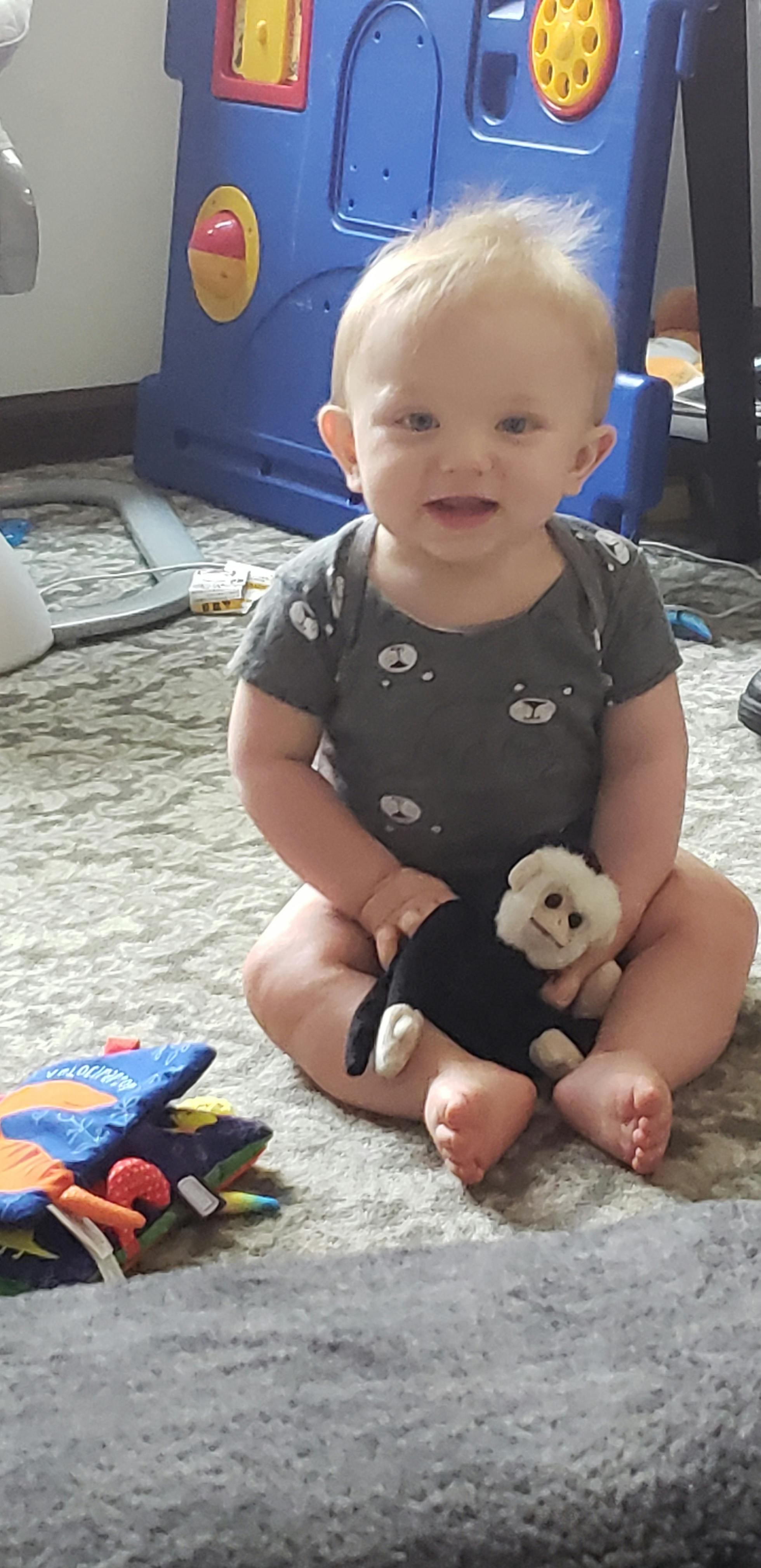 Child sitting on a rug holding a stuffed animal