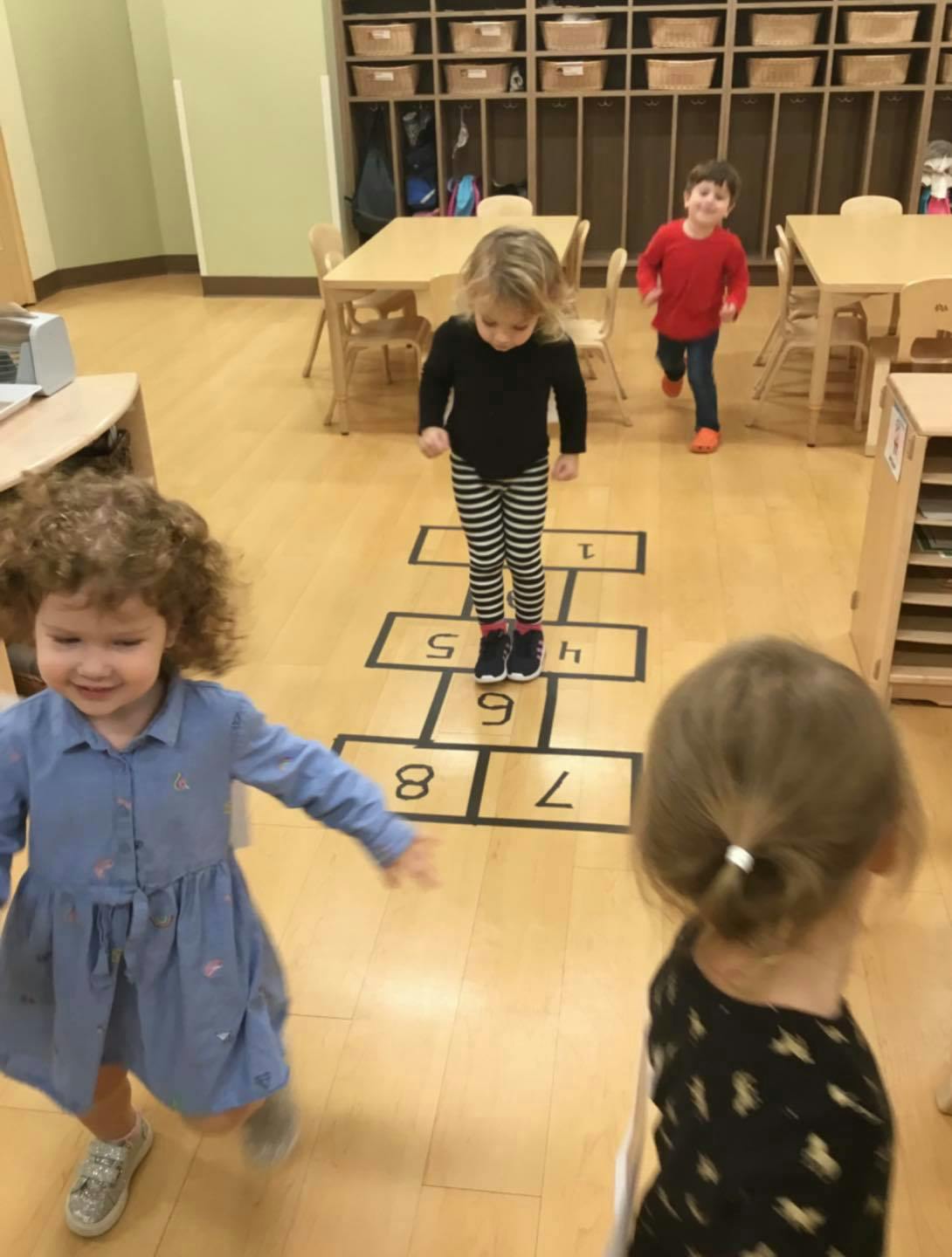 Child playing hopscotch in a classroom