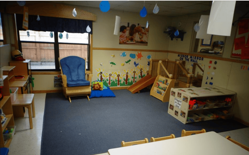 Playroom with a blue armchair, a small wooden slide, and shelves filled with toys