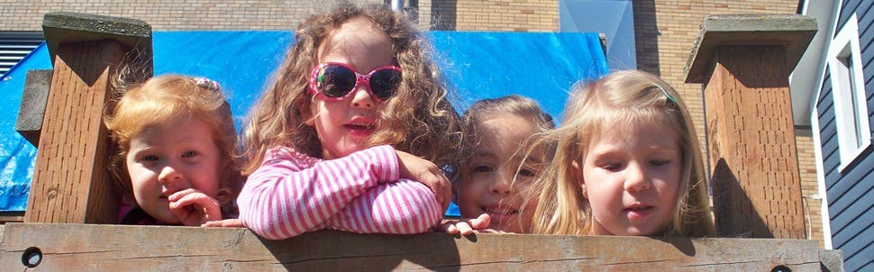 Four children looking over a wooden structure