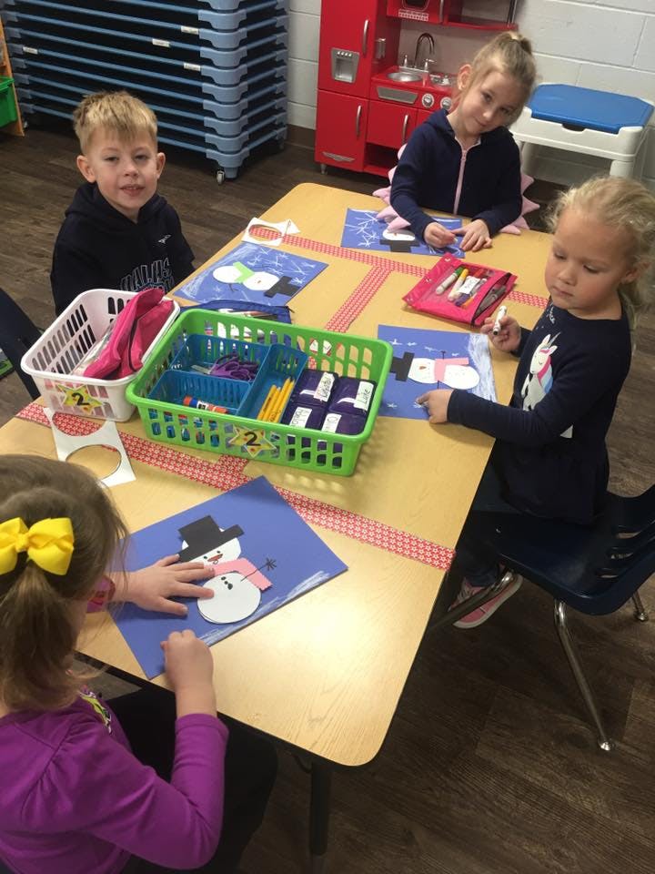 Children making snowman crafts at a table