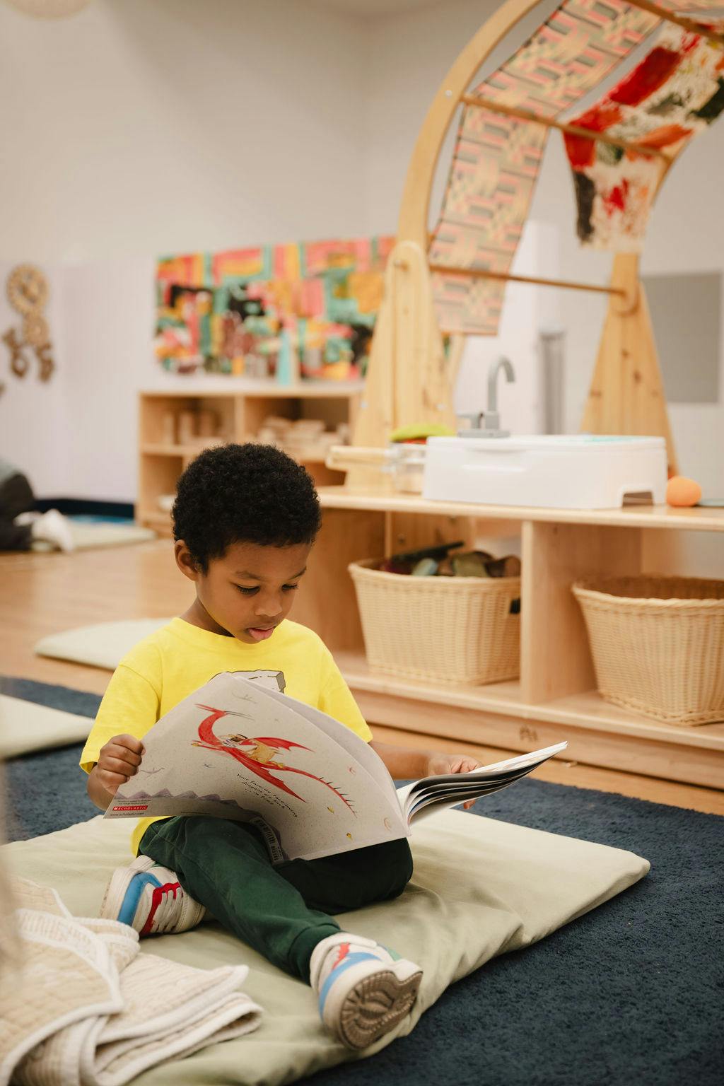 Child sitting on floor reading a book in a classroom