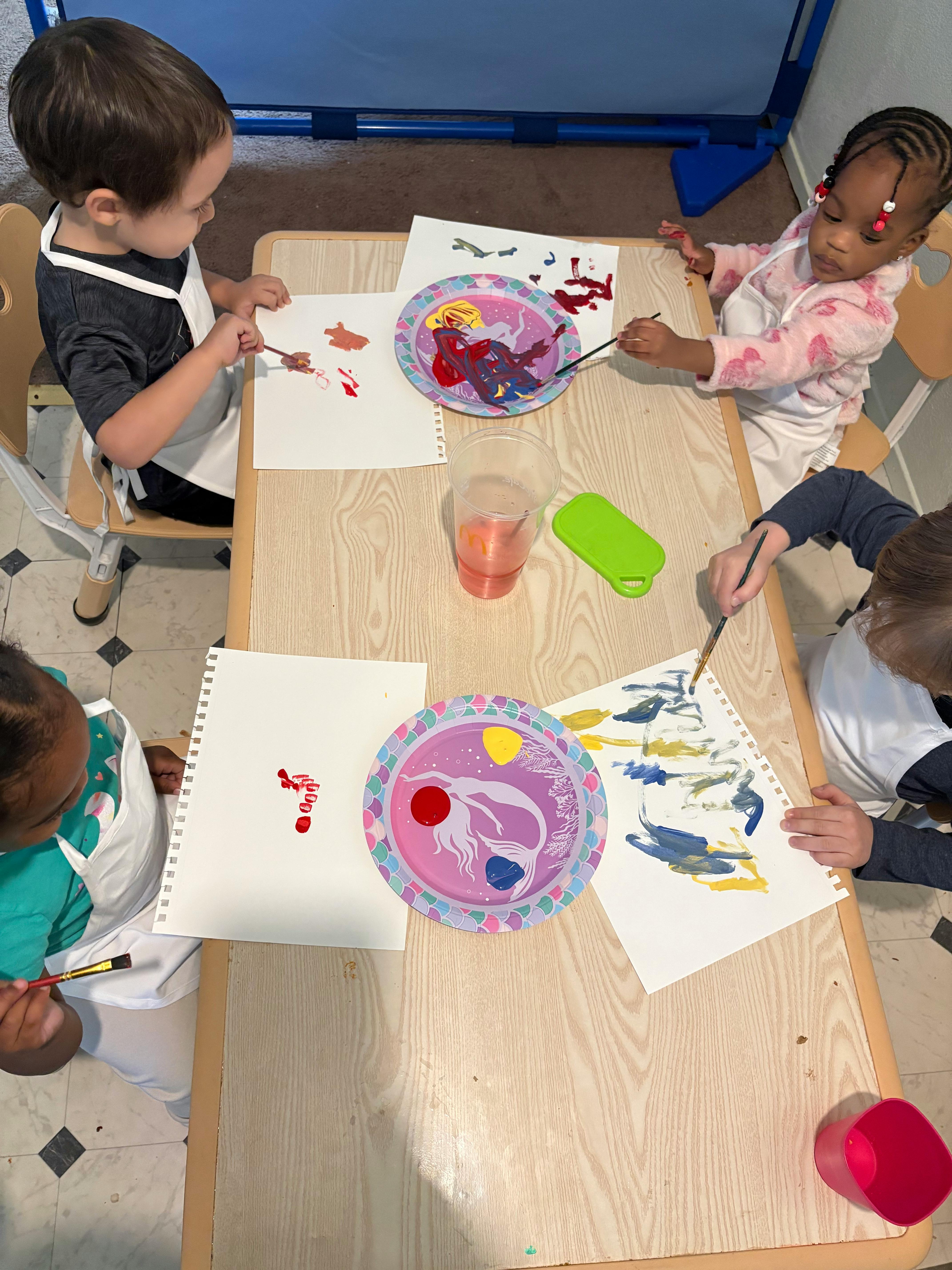 Four children painting at a table