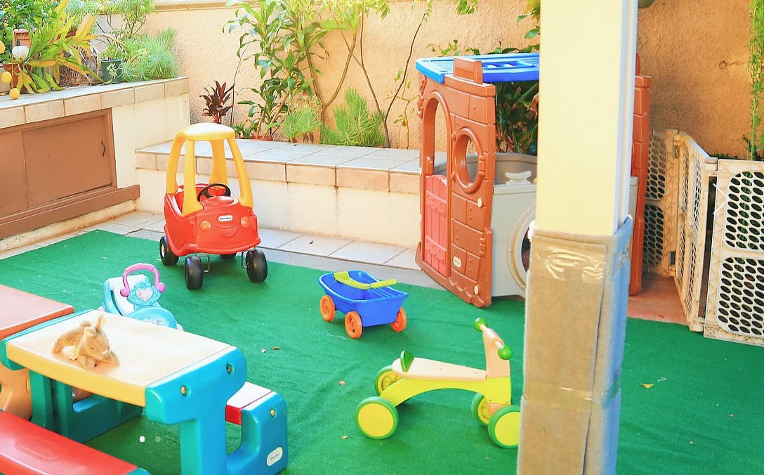 Outdoor play area with toy car, wagon, and ride-on toy