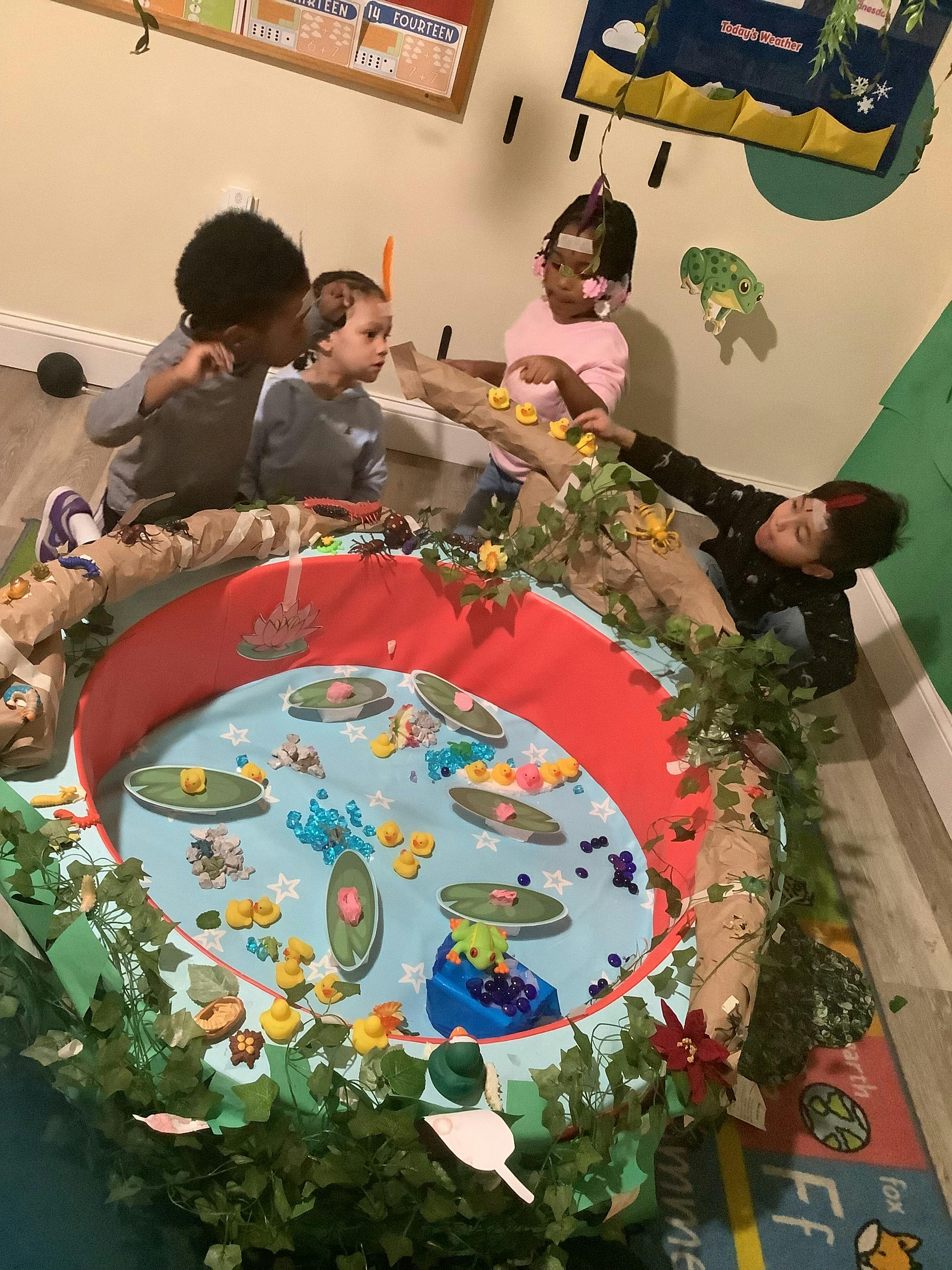 Children playing around a decorated sensory pond station in a classroom