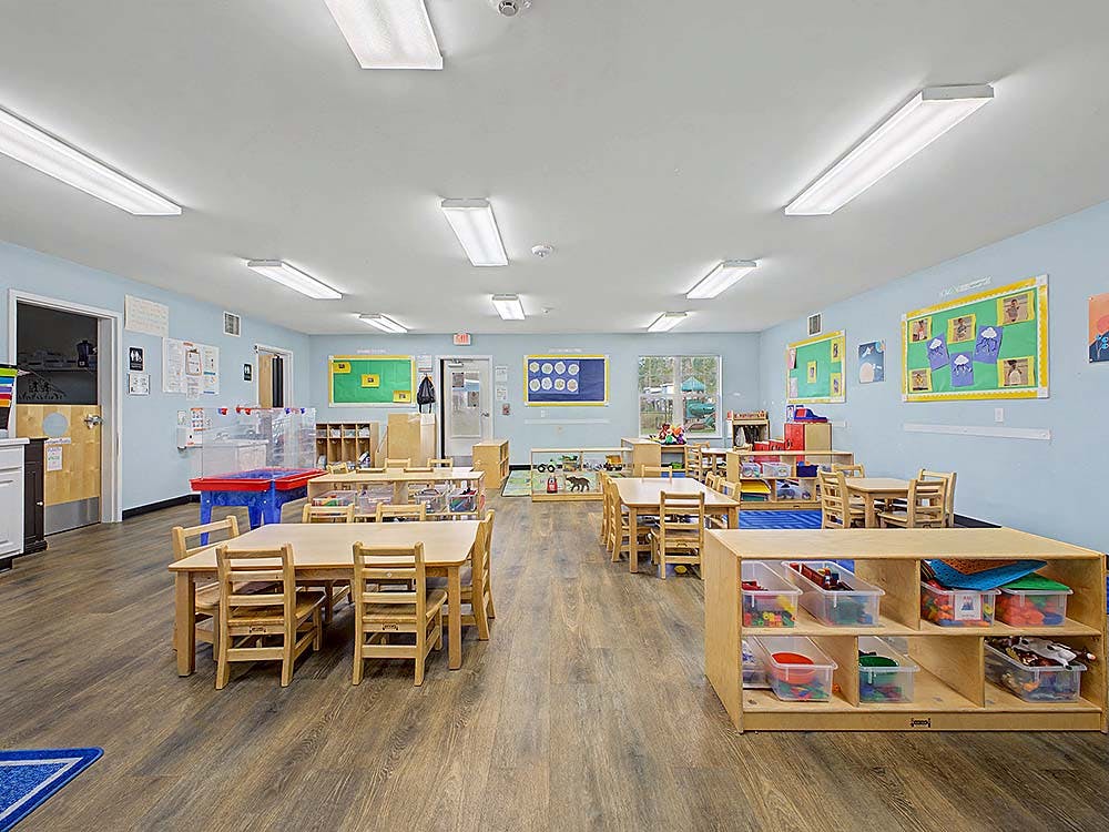 Empty classroom with small wooden tables and chairs, light blue walls