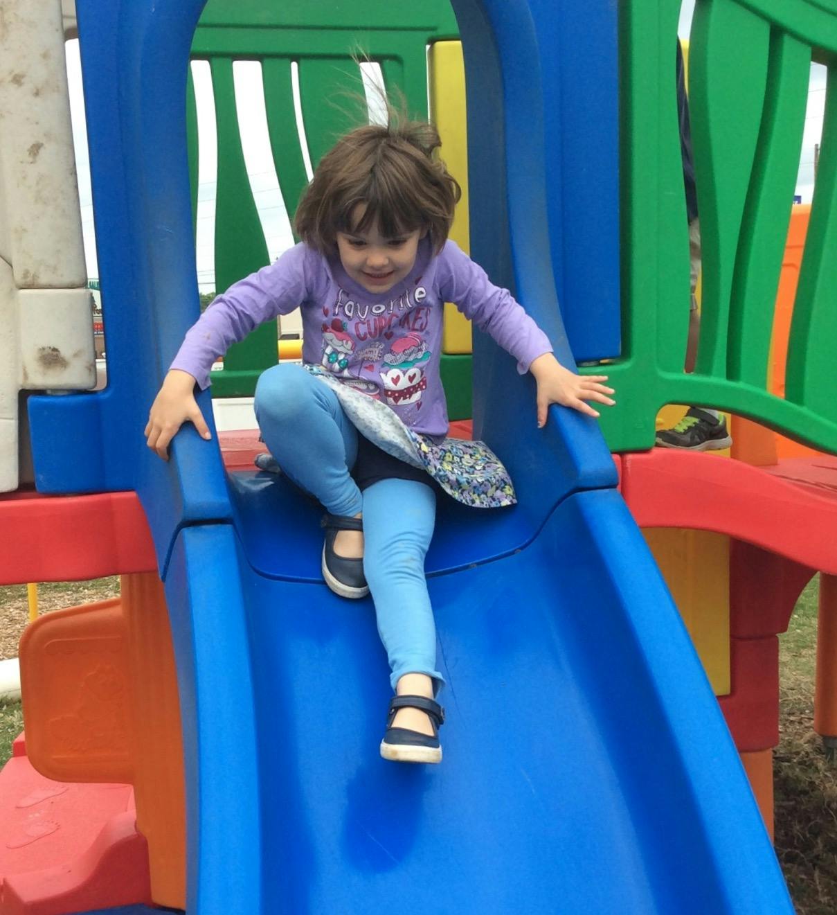 Child on a blue playground slide