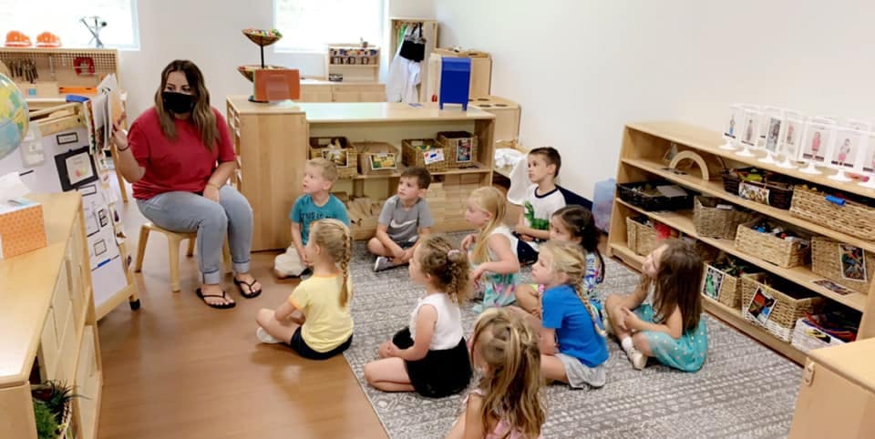 Person wearing a mask teaching children in a classroom
