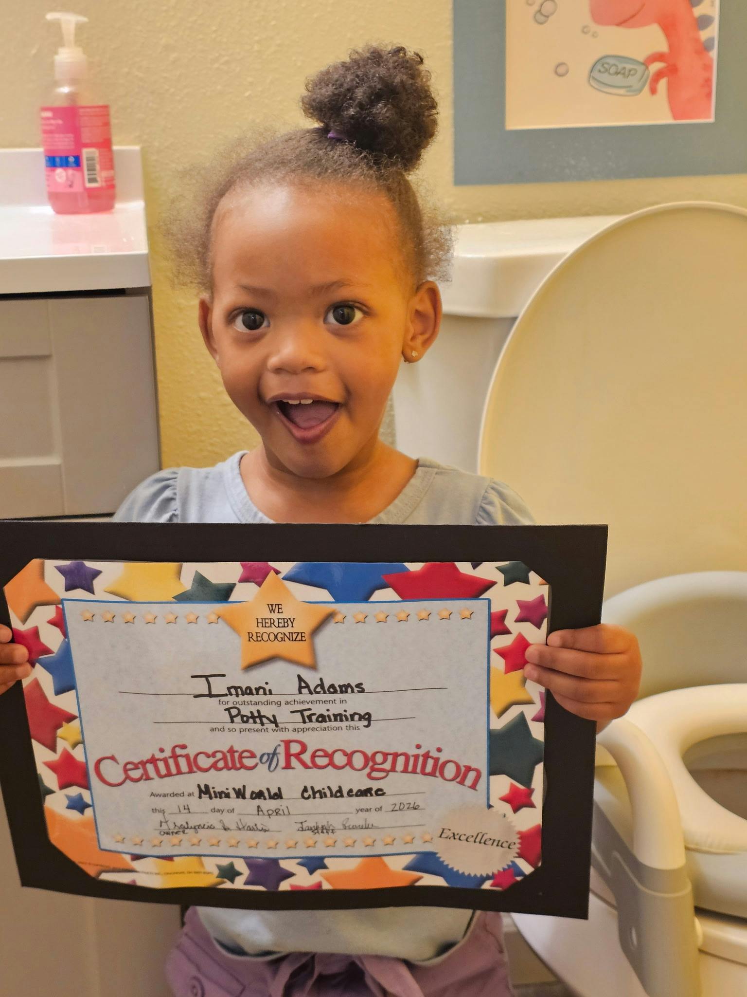 Child holding a potty training certificate of recognition