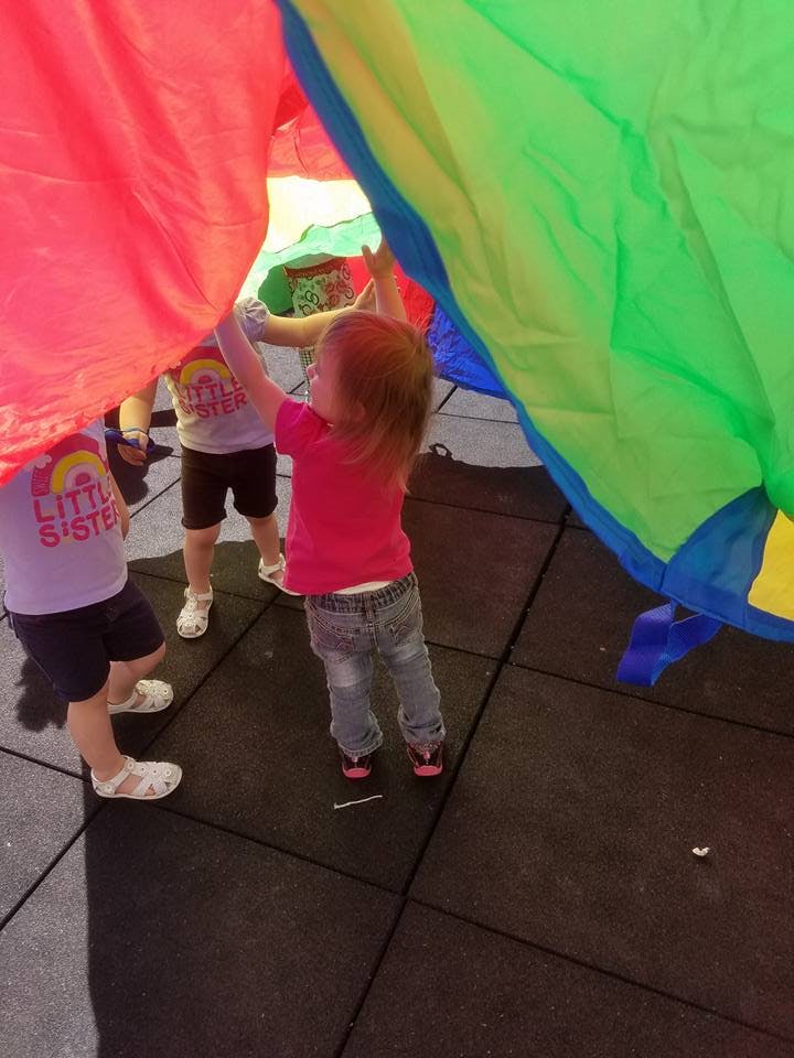 Children playing with a colorful parachute
