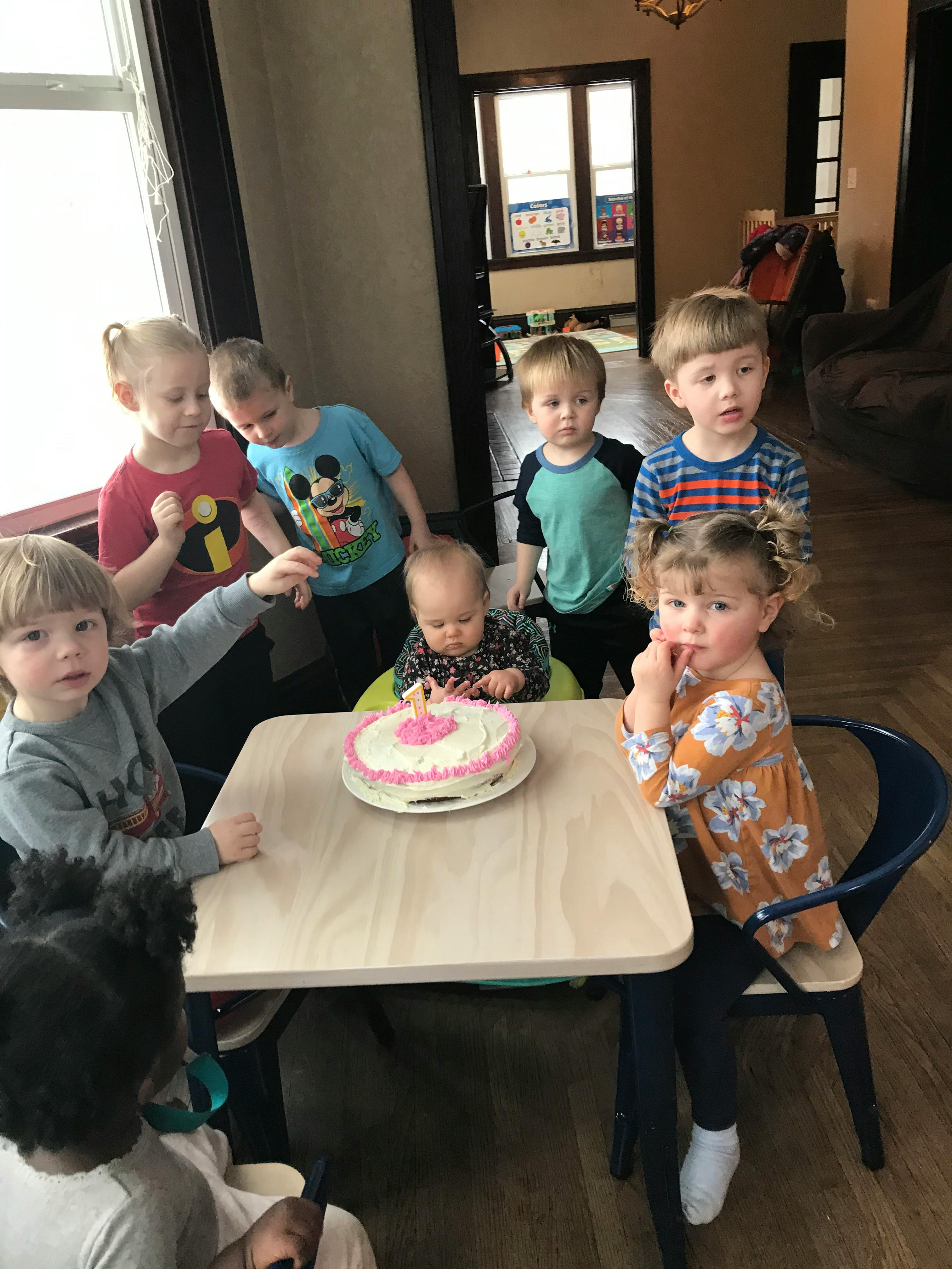 Children gathered around a table with a cake