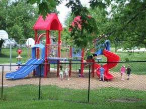 Children playing on a playground structure with slides and swings