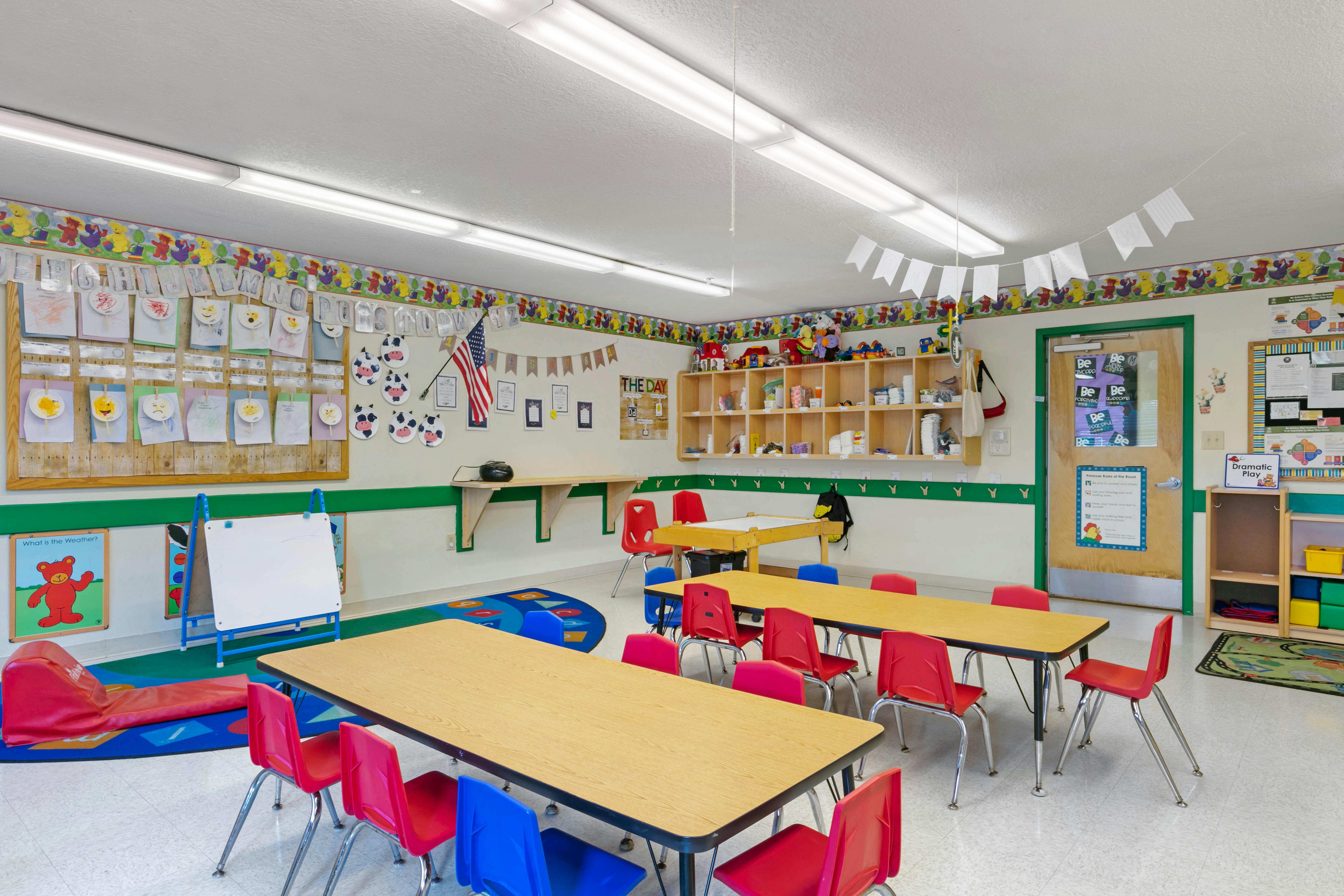 Empty colorful preschool classroom with small tables and chairs