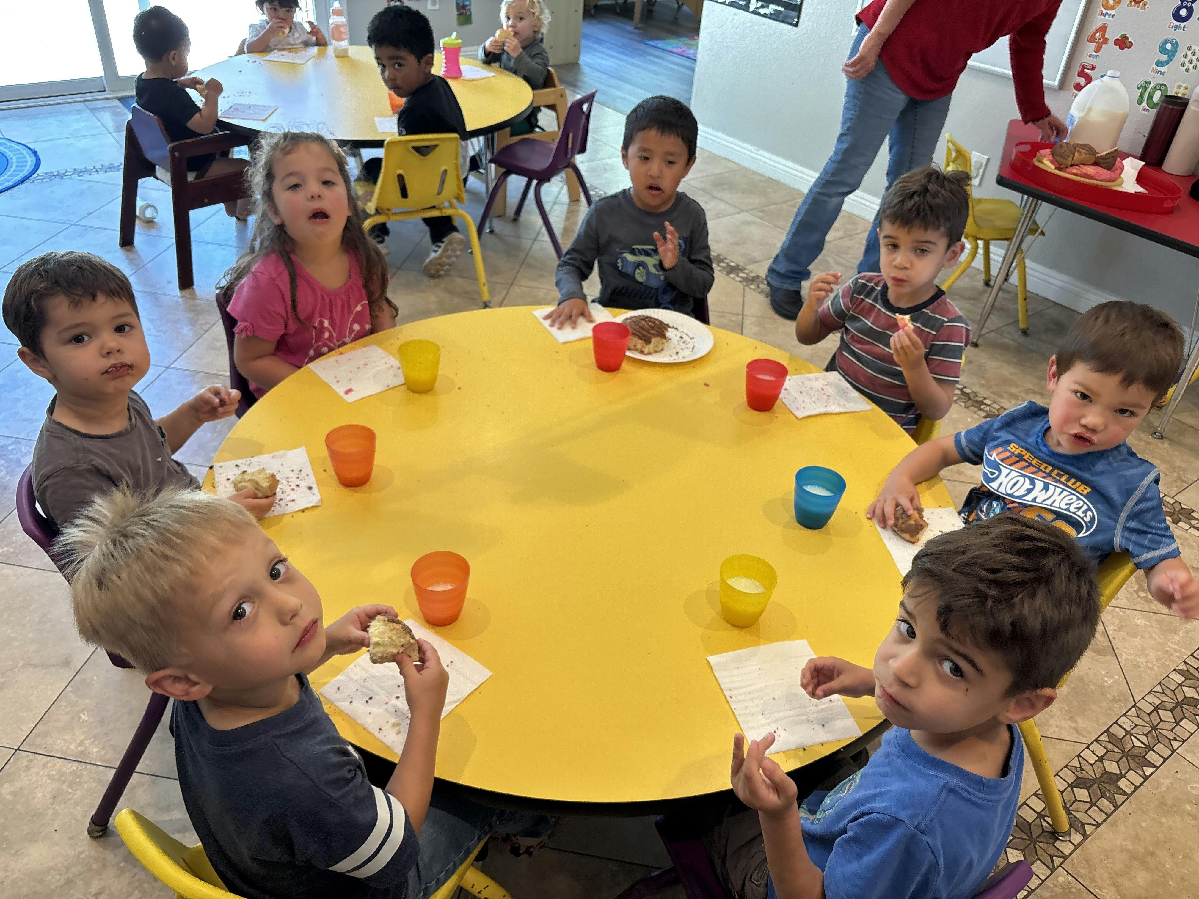 Children sitting at yellow tables eating