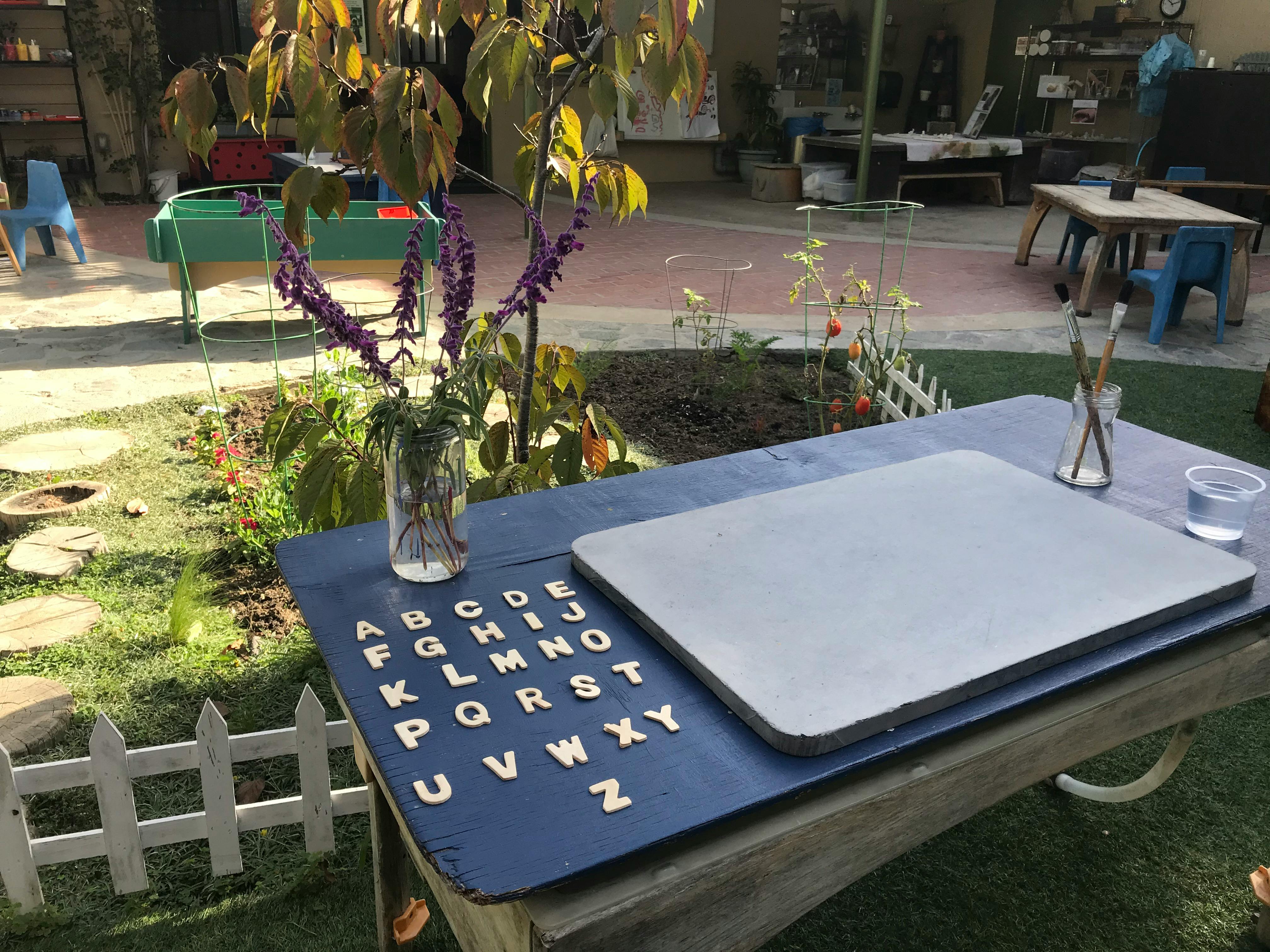 Table with alphabet letters, a blank board, and paintbrushes