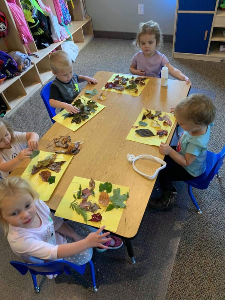Children at a table making crafts with leaves