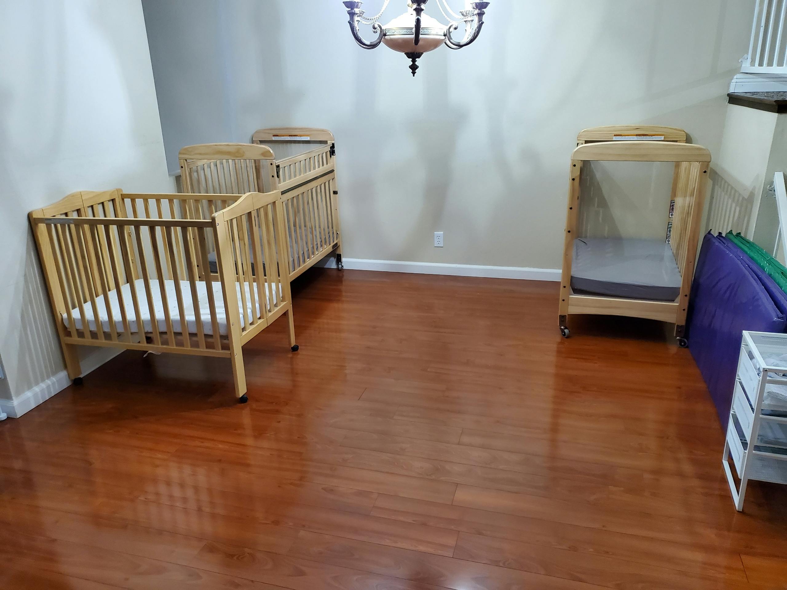 Three wooden cribs in a room with hardwood floors