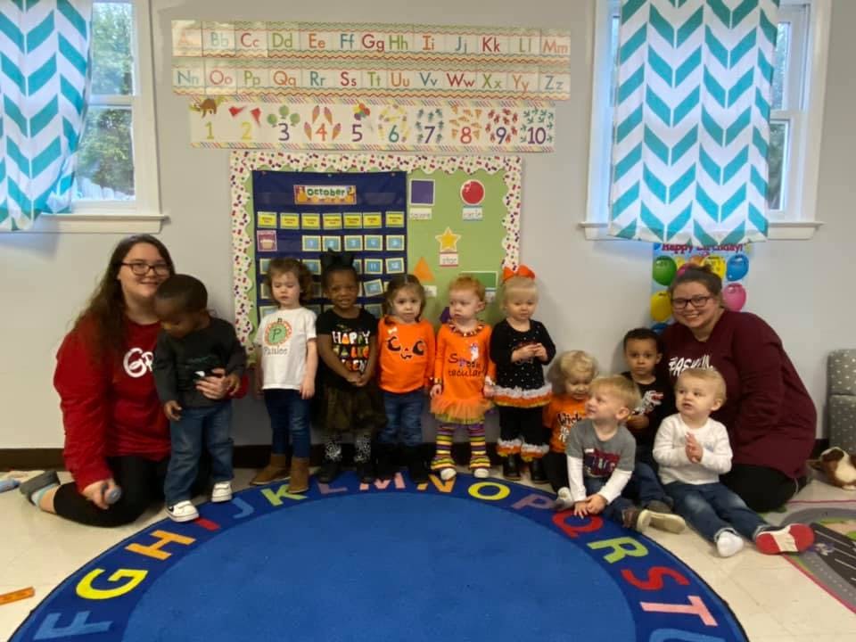 Two people with a group of children in a classroom